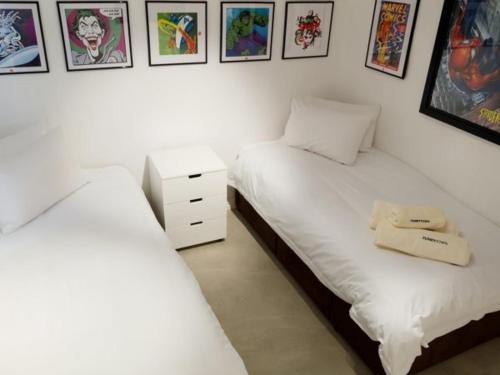 two beds in a room with pictures on the wall at Funky Town in Jeffreys Bay