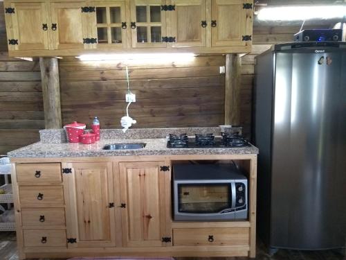a kitchen with a stove and a refrigerator at CHALÉ ESTÂNCIA OURO VERDE in Lages