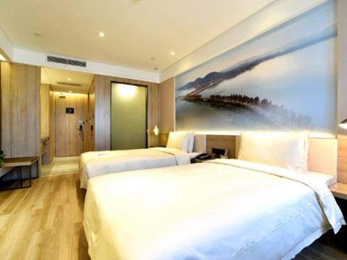 a hotel room with two beds and a painting on the wall at Atour Hotel Wuhan Changqing Road Branch in Wuhan
