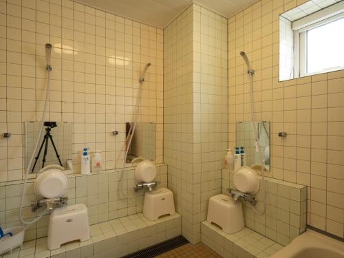 baño con 2 urinarios blancos y ventana en Shimanoyado Rebunshiri, en Rebun