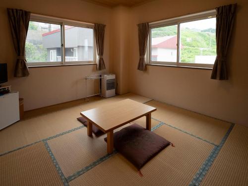 un soggiorno con tavolo e 2 finestre di Shimanoyado Rebunshiri a Rebun