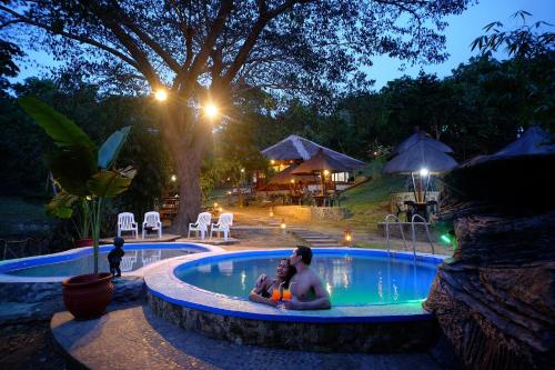 a man and woman sitting in a swimming pool at night at Villa Khadine Grand Vista Resort in Coron