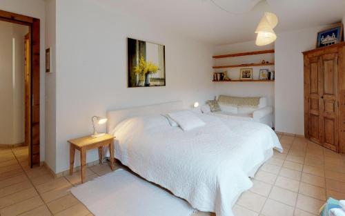 a bedroom with a large white bed and a chair at Nina in Celerina
