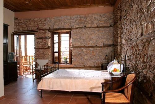 um quarto com uma cama grande numa parede de pedra em Archontiko Athina em Koumariá