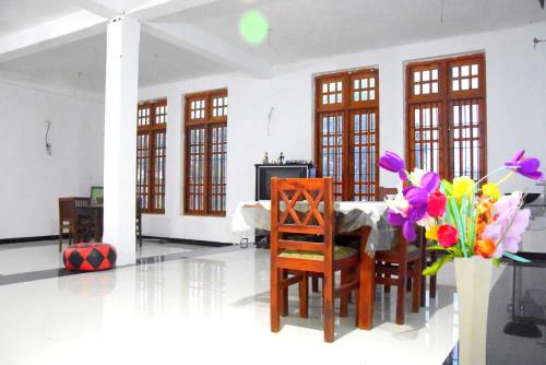 een eetkamer met een tafel en een vaas met bloemen bij Royal Views Residence in Anuradhapura