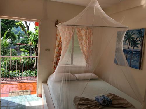 a bedroom with a canopy bed and a large window at Puerto Galera Hostel in Puerto Galera