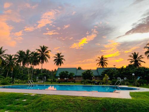 a swimming pool with a sunset in the background at Crown Holiday Village near Marawila in Nattandiya