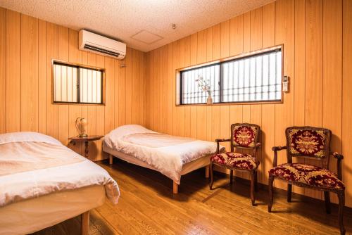 une chambre avec deux lits et deux chaises dans l'établissement 徐宅, à Nara