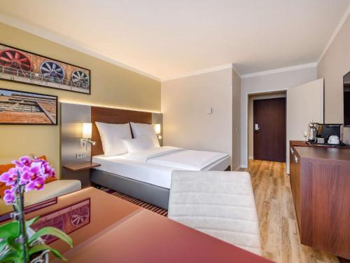 a hotel room with a large bed and a couch at Mercure Hotel Duisburg City in Duisburg