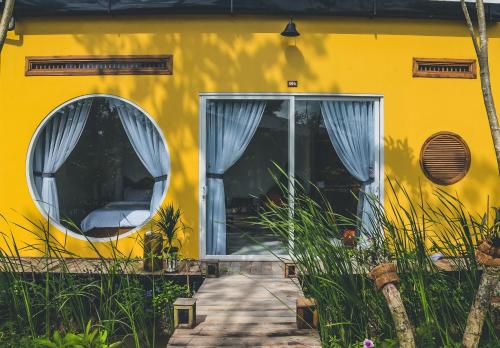 une maison jaune avec une porte et deux fenêtres dans l'établissement Binh Minh Eco Lodge, à Cần Thơ