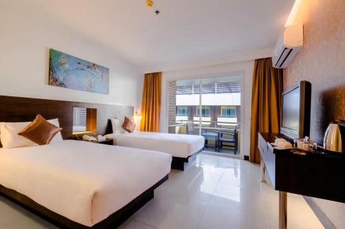 a hotel room with two beds and a television at Baron Beach Hotel in Pattaya