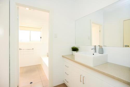a white bathroom with a sink and a mirror at Aldinga Beach Experience - C21 SouthCoast Holidays in Aldinga Beach