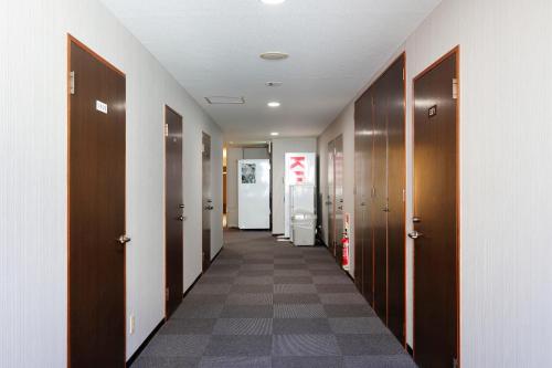a hallway with wooden doors and a tile floor at Tabist Rays Hotel Yakata in Miyazaki