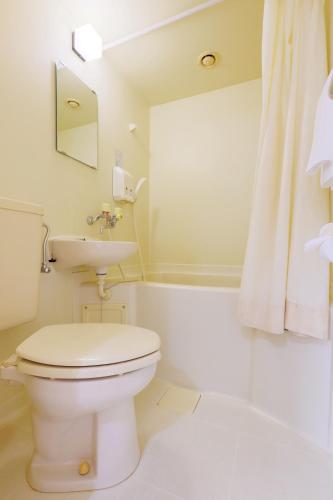 a white bathroom with a toilet and a sink at Tabist Rays Hotel Yakata in Miyazaki