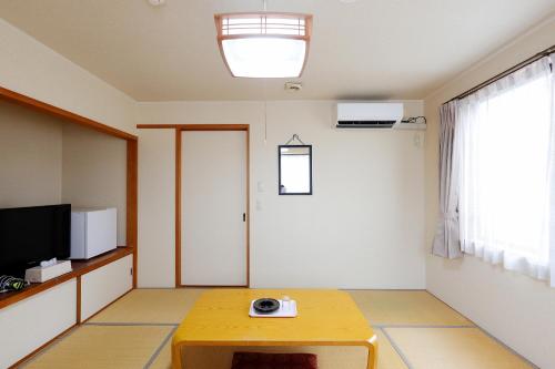 a room with a table and a television and a room at Tabist Rays Hotel Yakata in Miyazaki