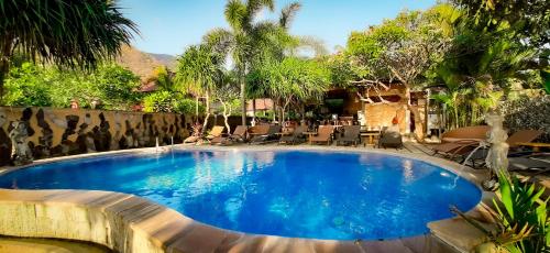 una piscina en un complejo con sillas y árboles en Bali Bhuana Beach Cottages, en Amed