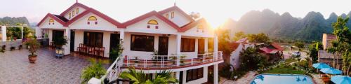 a large white house with mountains in the background at Lucky Homes in Phong Nha