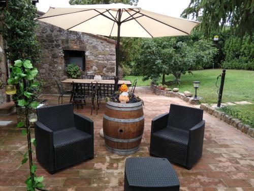 a wine barrel and two chairs and an umbrella at B&B la luna nel Pozzo in Todi