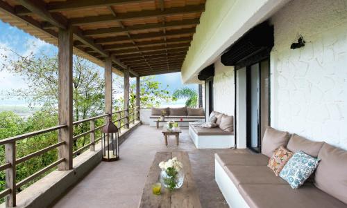 a patio with a couch and chairs on a balcony at Bungalow 89 by StayVista - A hill-view villa adorned with eclectic interiors for a truly unique & captivating stay in Lonavala
