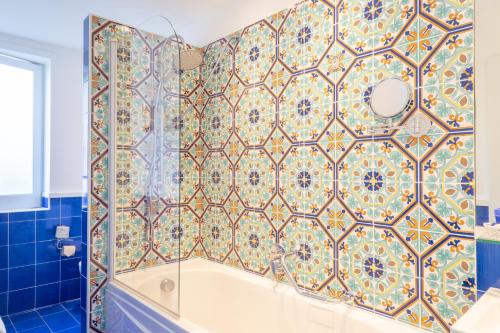 a bathroom with a tub and a tile wall at Boutique Hotel Regina in Sorrento