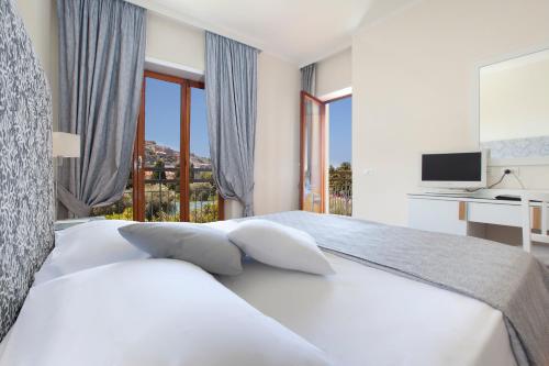 a white bedroom with a bed with a desk and window at Boutique Hotel Regina in Sorrento
