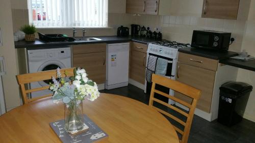 uma cozinha com uma mesa com um vaso de flores em Lerwick Garden Apartment em Inverness