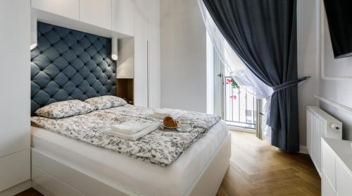 Schlafzimmer mit einem großen Bett mit blauem Kopfteil in der Unterkunft MY KRAKOW Apartments - Topolowa 8 in Krakau