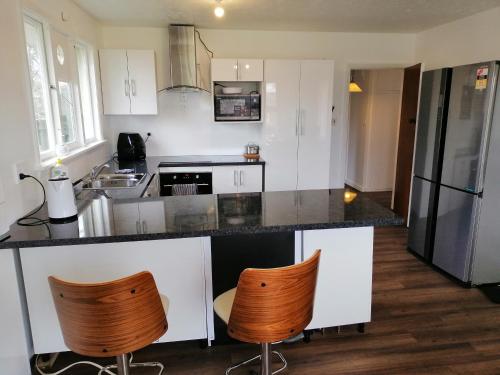 una cocina con armarios blancos y encimeras negras en Homestay Family room, near the city center en Christchurch