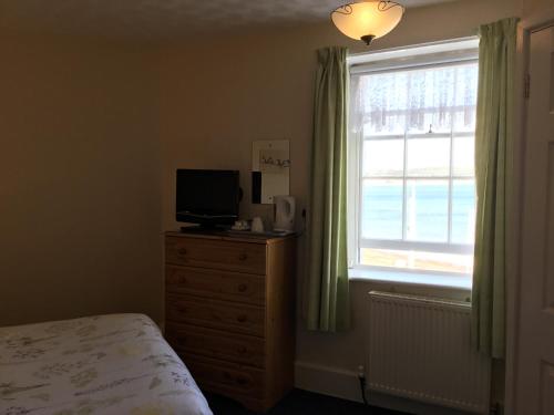 a bedroom with a bed and a television and a window at Cavendish House in Weymouth
