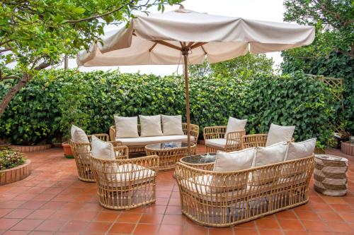 a patio with wicker chairs and an umbrella at Boutique Hotel Regina in Sorrento