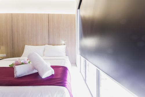 a hotel room with a bed with white sheets and flowers at GM Hotel Kuantan in Kuantan