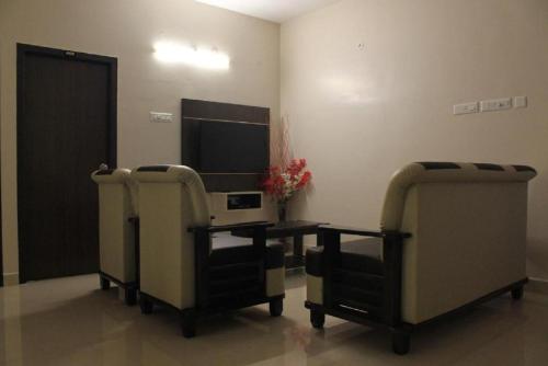 a room with two chairs and a table and a tv at Viswa Residency by Azalea in Madurai
