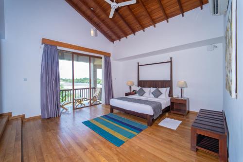 a bedroom with a bed and a balcony at Amaranthe Bay Resort & Spa in Trincomalee