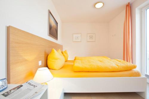a bedroom with a bed with yellow pillows on it at Jann-Berghaus-Straße 29 in Norderney