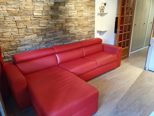 un sofá rojo en una sala de estar con una pared de ladrillo en Le Serac W6 appartement avec véranda en angle vue panoramique gérer par particulier sur place en Val Thorens