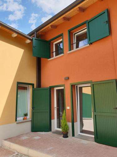 un edificio naranja con puertas y ventanas verdes en La Corte del Sant'Orsola, en Bolonia