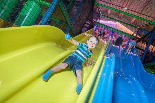 a young child sliding down a slide on a playground at Schlosshotel Lacknerhof in Flachau