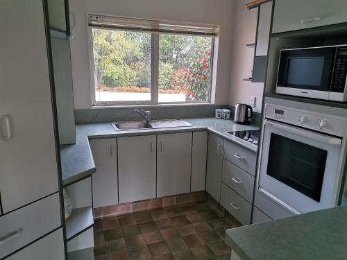 a kitchen with white cabinets and a sink and a window at Mattanna Apartment in Rangiora