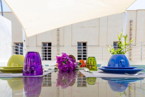 a table with colorful plates and flowers on it at B&B Cantiere dell'anima - Rooms of art in Trapani