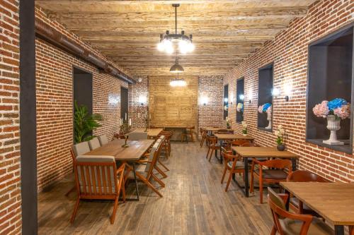 a restaurant with wooden tables and chairs and brick walls at Royal Inn in Tbilisi City