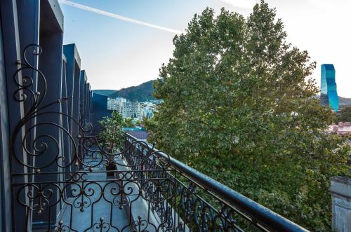 a balcony with a wrought iron railing and a tree at Royal Inn in Tbilisi City