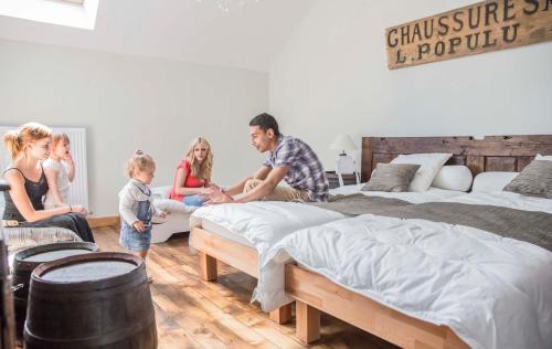 a family sitting around a bedroom with two beds at Gîte de La Jéraphie in La Souterraine