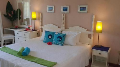 um quarto com uma cama branca com almofadas azuis e verdes em Deluxe studio 228 em Negril