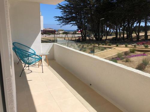 einem blauen Stuhl auf einem Balkon mit Meerblick in der Unterkunft Departamento Nuevo in El Tabo