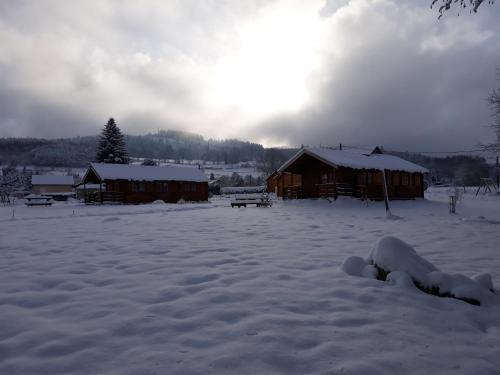 a snow covered field with a cabin in the background at chalets les 5 loups in Gerbépal