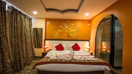 um quarto com uma cama grande e almofadas vermelhas em Hotel Royal Safari em Sauraha