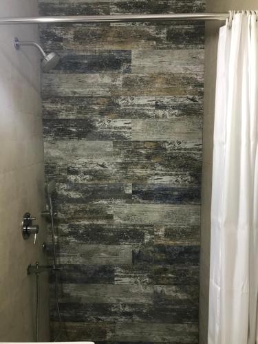 a bathroom with a shower with a wooden wall at Tatvamasi Homestay in New Delhi