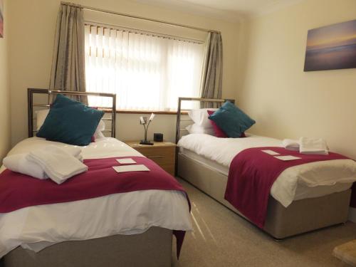a bedroom with two beds and a window at Rose Vean Bed & Breakfast in Helston