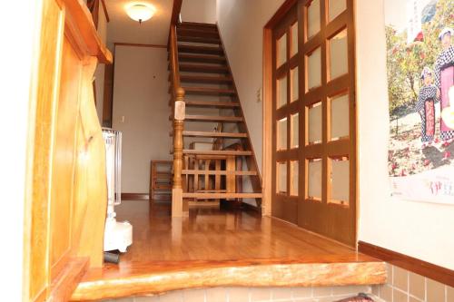 a hallway with a wooden staircase with a wooden door at 陽のあたる宿 サンセットパーム in Oshima