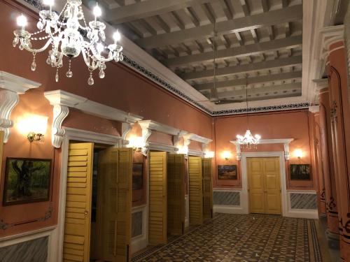a hallway with yellow doors and a chandelier at COSSIMBAZAR PALACE OF THE ROYS ( RAJBARI) in Cossimbāzār
